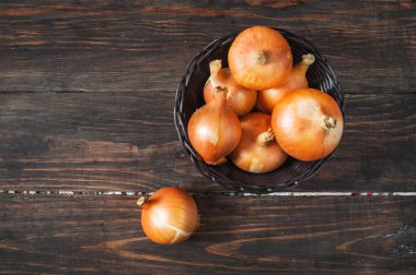 Ahşap masa üzerinde bir sepet içinde ham altın soğan.