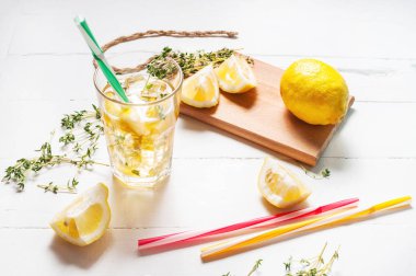 Beyaz ahşap bir masa üzerinde bir saman ile bardakta servis kekik ile limonata.