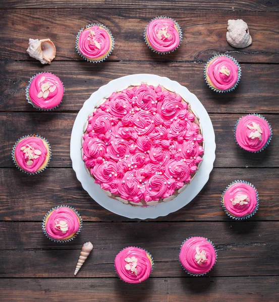 Pasteles y cupcakes con crema rosa sobre fondo rústico de madera. Pasteles rosados . — Foto de Stock