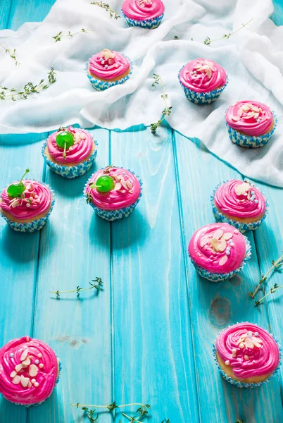 Cupcakes de color rosa sobre fondo de madera azul — Foto de Stock