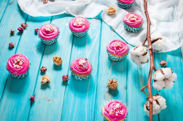 Cupcakes rosa colorido no fundo de madeira azul — Fotografia de Stock