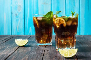 Ev yapımı Cuba Libre taze limon ile kahverengi ROM ve eski ahşap masa kırılmış buz