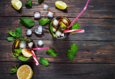 Ev yapımı Cuba Libre taze limon ile kahverengi ROM ve eski ahşap masa kırılmış buz