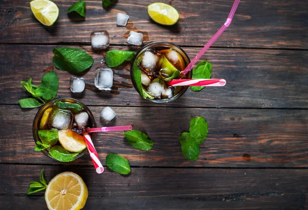 Ev yapımı Cuba Libre taze limon ile kahverengi ROM ve eski ahşap masa kırılmış buz
