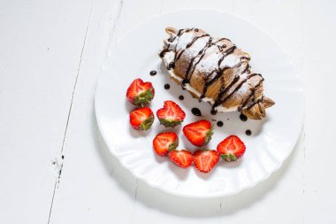 Lezzetli kahvaltı taze kruvasanlar ve Beyaz ahşap zemin üzerinde taze çilek ile.