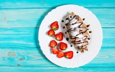 Lezzetli kahvaltı taze kruvasanlar ve mavi ahşap zemin üzerine taze çilek ile