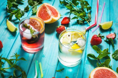 Alkol soğuk kokteyl bardak buz, meyve ve ahşap masa üzerinde kalan nane ile dekore edilmiştir. Limon, çilek, kireç zemin üzerine taze meyve suyu