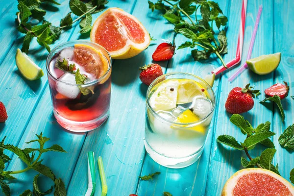 Alkol soğuk kokteyl bardak buz, meyve ve ahşap masa üzerinde kalan nane ile dekore edilmiştir. Limon, çilek, kireç zemin üzerine taze meyve suyu