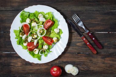 Caprese salatası. Kiraz domates, Bebek ıspanak ve mozzarella rustik ahşap zemin, pesto sosu ile metal kapta görünümü üst
