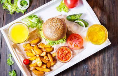 Taze ev yapımı hamburger, patates kızartması, bira ve suyu beyaz tepside servis