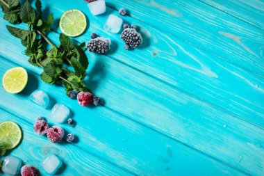 taze çilek, kireç, mavi ahşap zemin üzerine nane ve buz küpleri.
