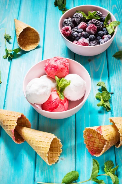 Ice cream in bowl, berries and waffle cones on blue wooden table. Summer — Stock Photo, Image