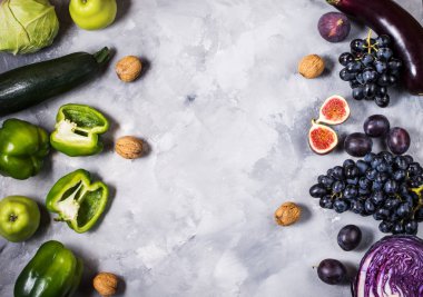 Taze organik çiğ yeşil ve mor renkli sebze ve meyve taş zemin üzerine. Üstten Görünüm. Boşaltmak.