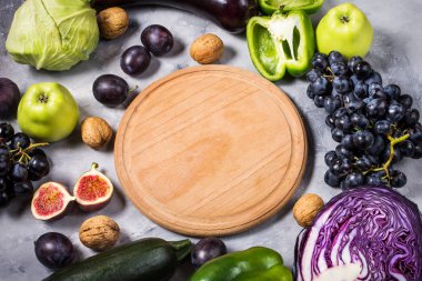 Taze organik çiğ yeşil ve mor renkli sebze ve meyve taş zemin üzerine.