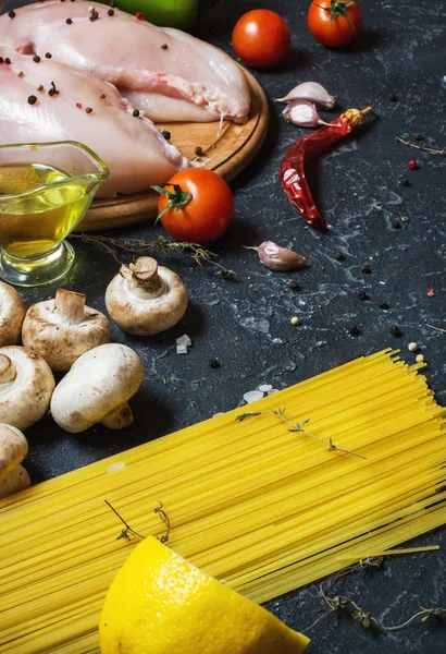 Makarna malzemeler. Tavuk göğsü, Cherry Domates, spagetti makarna ve meyveleri koyu taş masanın üzerine