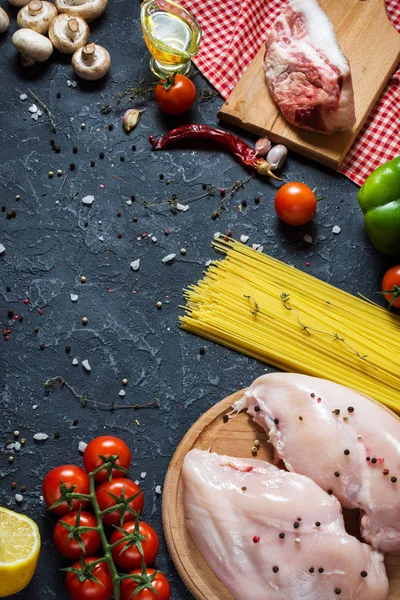 Makarna malzemeler. Tavuk göğsü, Cherry Domates, spagetti makarna, pastırma ve taş masanın üzerinde mantar.