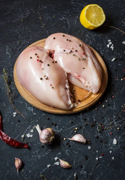 Taze çiğ tavuk fileto, baharatlar ve otlar siyah taş zemin üzerine