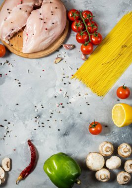 Makarna malzemeler. Tavuk göğsü, Cherry Domates, spagetti makarna ve mantar taş masanın üzerine.