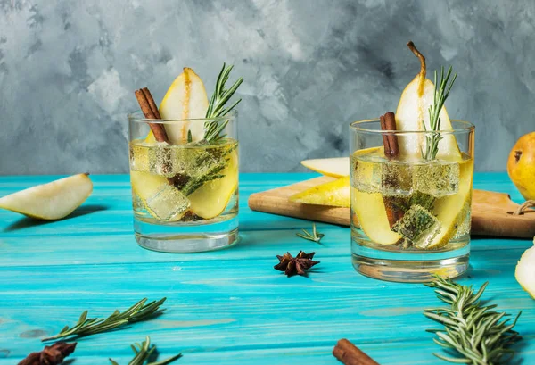 Coquetel de pêra com rum, licor, fatias de pêra e alecrim em uma mesa de madeira azul — Fotografia de Stock