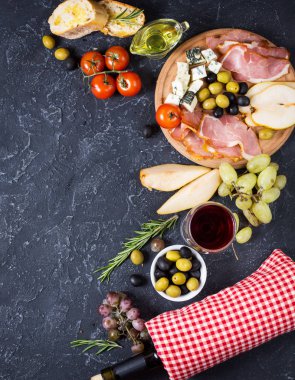 Meze, İtalyan meze, jambon, zeytin, peynir, ekmek, üzüm, armut ve karanlık taş zemin üzerine şarap. Üstten Görünüm