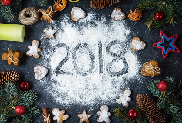 Happy New Year 2018 written on flour and Christmas Decorations Gingerbread cookies on dark stone background. Christmas card, New Year greeting card.