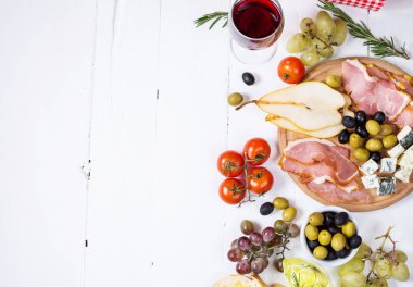 Meze, İtalyan meze, jambon, zeytin, peynir, ekmek, üzüm, armut ve şarap Beyaz ahşap zemin üzerinde