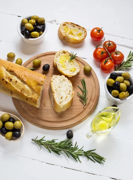 Black and green olives in wooden bowls on wood white background.