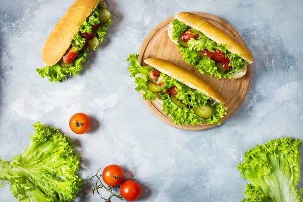 Hot dog con sottaceti e lattuga su sfondo di cemento — Foto Stock