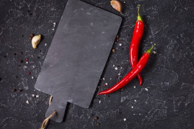 Kesme tahtası ve kırmızı sıcak biber pepeprs siyah taş arka planda, üstten görünüm