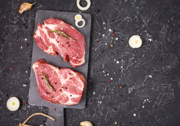 Filete de carne cruda con condimentos sobre fondo de piedra negra. Espacio para el texto. Filete listo para cocinar. Concepto de barbacoa. Ingredientes para el tostado de carne . —  Fotos de Stock