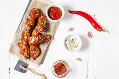 Beyaz ahşap zemin üzerinde soslu tavuk kanadı pişmiş. Kopya alanı.