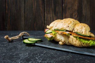 Kruvasan peynir, jambon, salatalık ve bir taş zemin üzerine salata ile