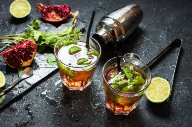 Ferahlatıcı mojito garnet, nane ve içecekler kırbaçlanan Çalkalayıcı ile koyu gri taş tabloda kireç kokteyl
