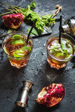 Ferahlatıcı mojito garnet, nane ve içecekler kırbaçlanan Çalkalayıcı ile koyu gri taş tabloda kireç kokteyl