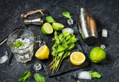 Mojito kokteyl yapımı. Nane, limon, cam, buz, malzemeler ve shaker taş zemin üzerine