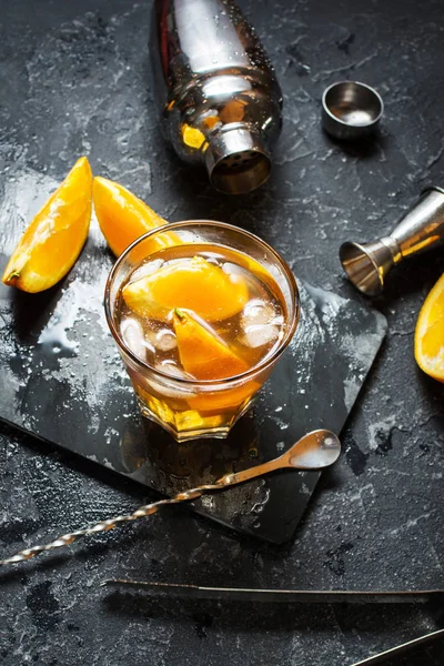 Um copo de coquetel Negroni com laranja e limão. Bebida alcoólica com rum e vermute na mesa de pedra escura — Fotografia de Stock