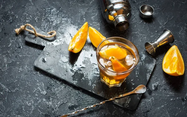 Бокал негрони с апельсином и лимоном. Алкогольный напиток с ромом и вермутом на тёмном каменном столе. С пробелами для текста — стоковое фото