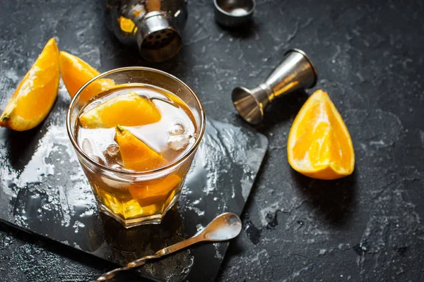 Egy pohár Negroni koktél, narancs és a citrom. Alkoholos ital, a rum és a sötét kő asztal vermut — Stock Fotó