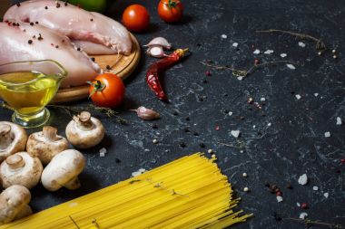 Makarna malzemeler. Tavuk göğsü, Cherry Domates, spagetti makarna ve meyveleri koyu taş masanın üzerine