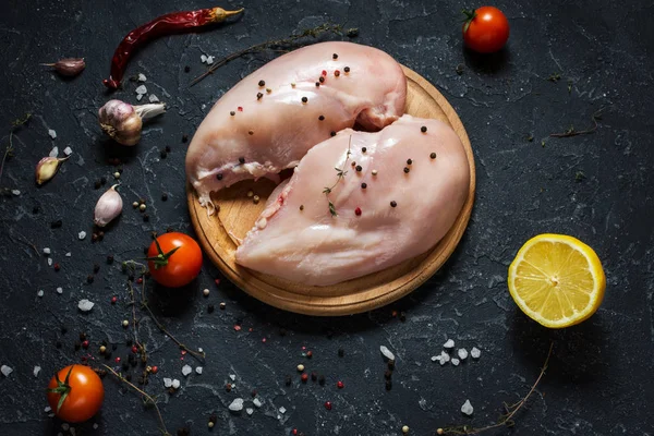 Fresh raw chicken fillet, spices and herbs on black stone background — Stock Photo, Image