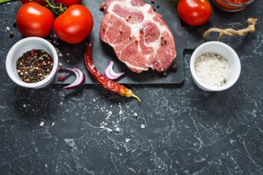 Karanlık taş arka plan üzerinde yemek pişirmek için malzemelerle çiğ mermer et biftek