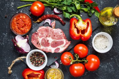 Karanlık taş arka plan üzerinde yemek pişirmek için malzemelerle çiğ mermer et biftek.