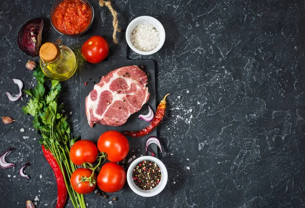 Filete de carne de mármol crudo con ingredientes para cocinar sobre fondo de piedra oscura —  Fotos de Stock