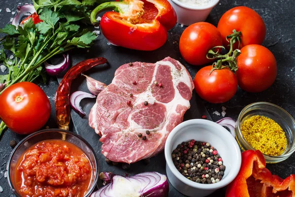 Karanlık taş arka plan üzerinde yemek pişirmek için malzemelerle çiğ mermer et biftek