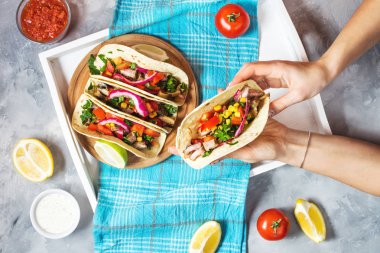 Eller Meksika domuz tacos sebze ile tutun. Tacos al papazı mavi ahşap rustik arka plan üzerinde. Sayfanın Üstü