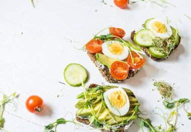 Yumurta, avokado ve sebze ahşap beyaz rustik arka planda lezzetli sandviçler.