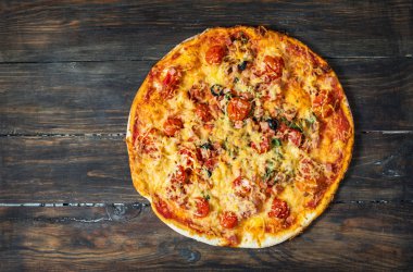 Dilimleri lezzetli taze domates ve pizza zeytin karanlık bir arka plan üzerinde kesmek. Üstten Görünüm. Pizza ahşap masa üzerinde.