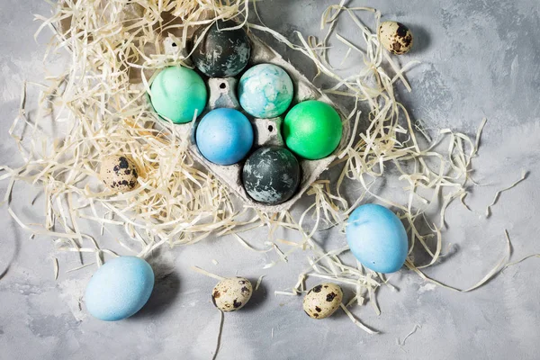 painted eggs in tray, quail and chicken eggs, paint and brush on concrete surface, Easter decorations