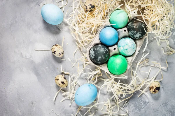 painted eggs in tray, quail and chicken eggs, paint and brush on concrete surface, Easter decorations