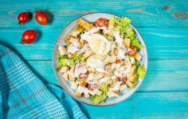 Plaka mavi ahşap masa üzerinde taze Sezar salatası. Sayfanın Üstü